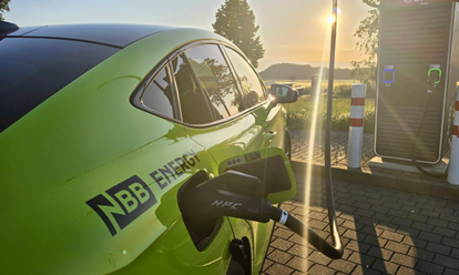NBB ENERGY Auto lädt an E-Ladesäule bei Sonnenuntergang